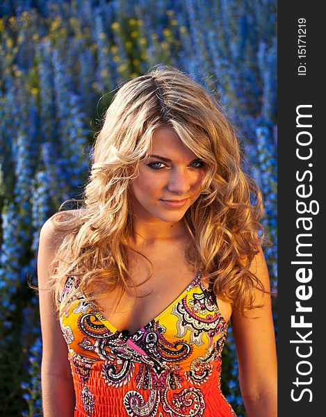 Portrait of a blue-eyed blonde young woman on a background of blue wild flowers. summer, outdoors.