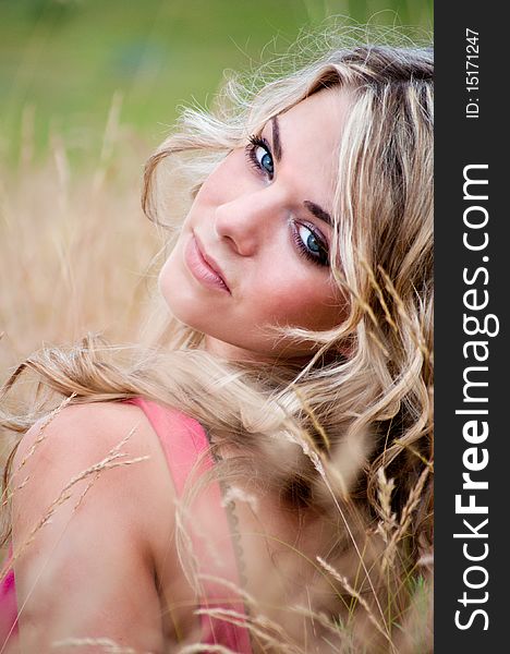 Portrait of a blue-eyed blonde young woman on a meadow background