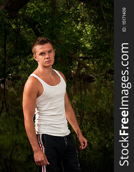 Young man in a white shirt on a background of forest. Young man in a white shirt on a background of forest