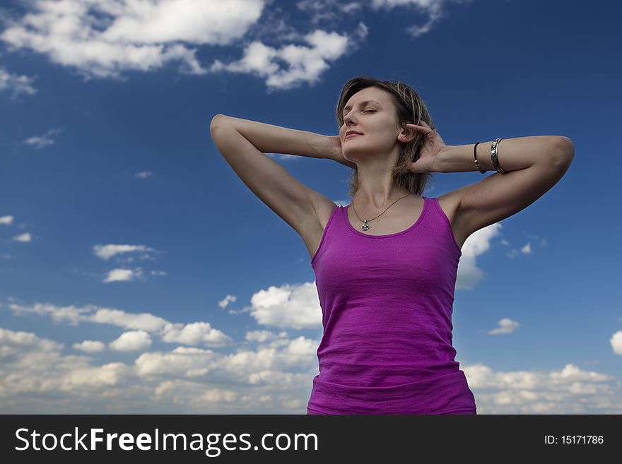 Young female stretching her arms against blue cloudy sky. Young female stretching her arms against blue cloudy sky