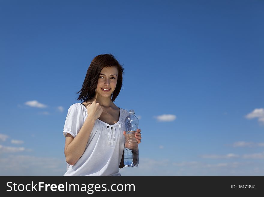 Young female with bootle of water against blue sky