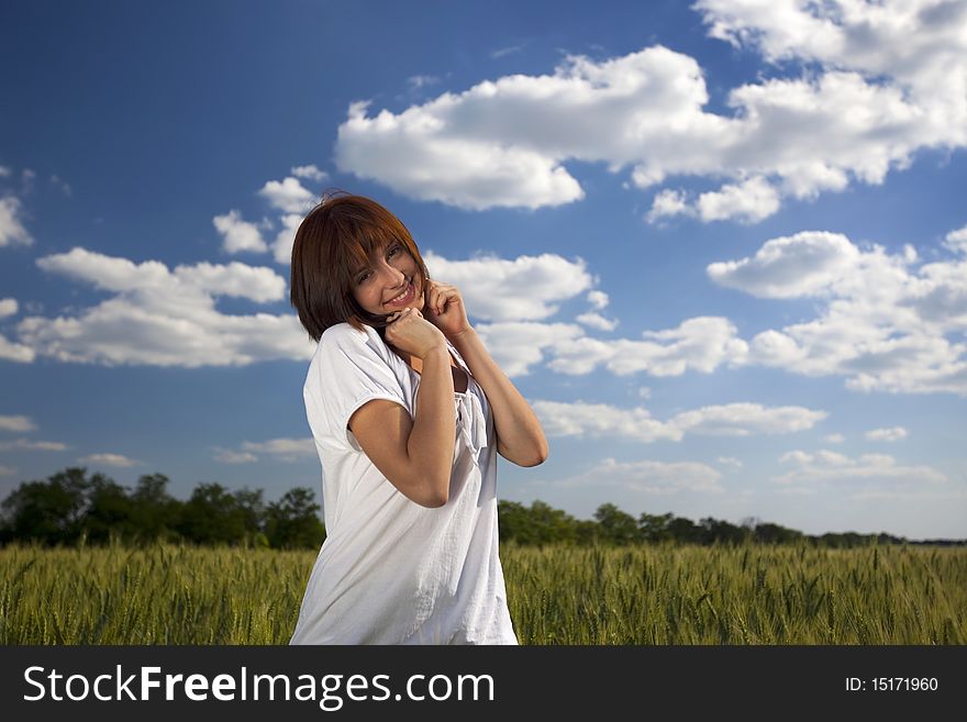 Young female smiling against blue sky and yellow wheat field. Young female smiling against blue sky and yellow wheat field