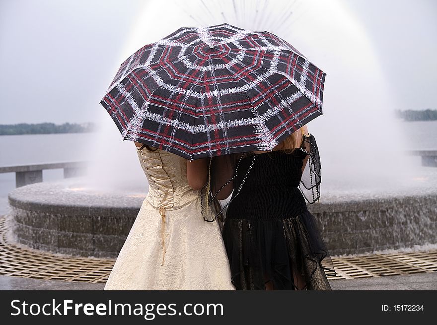 Two girls standing under a nice umbrella. Two girls standing under a nice umbrella.