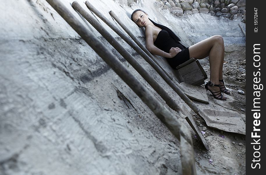 Sexual girl in black dress inside stone quarry among old shovels. Photo.