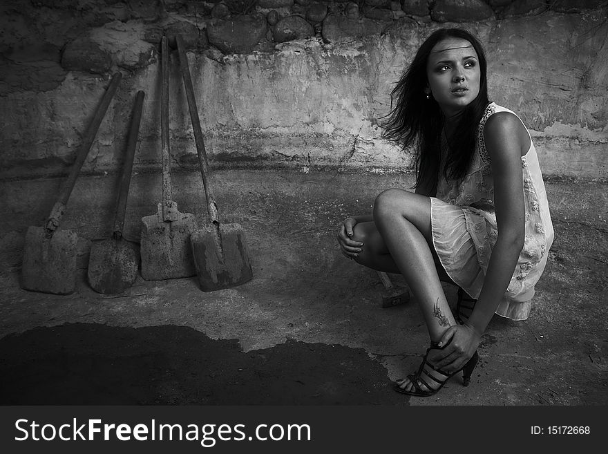 Sexual girl in black dress inside stone quarry among old shovels. Photo.