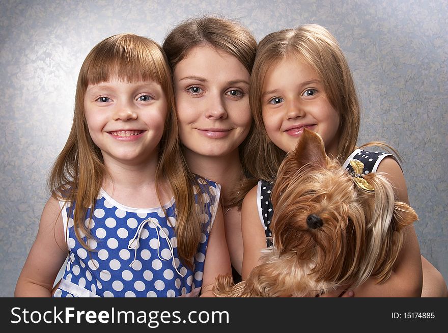 Young mother and two little sisters with Yorkshire terrier over light defocused background. Young mother and two little sisters with Yorkshire terrier over light defocused background