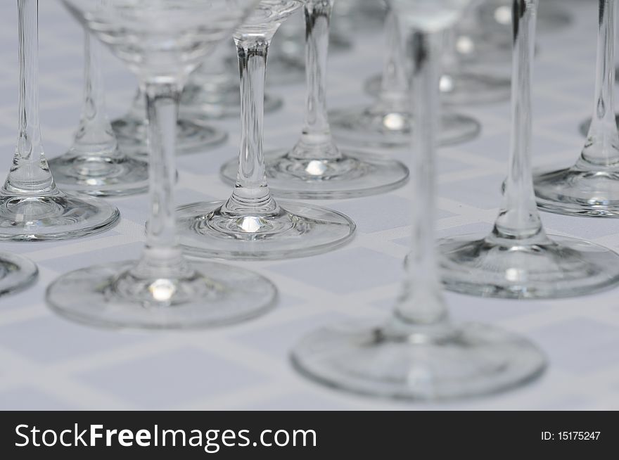 Abstract rows of legs of wineglasses on the white table