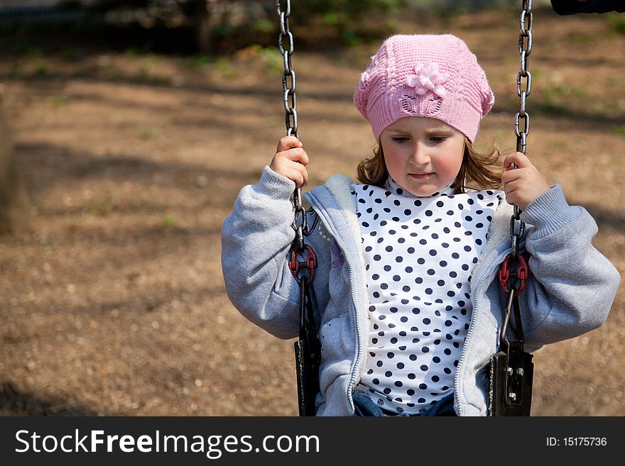 Little girl enjoying the swing in a spring day in the park. Little girl enjoying the swing in a spring day in the park.