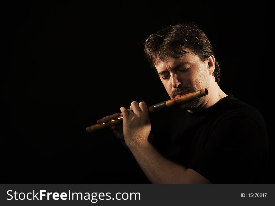 Man in black plays a wooden flute. Man in black plays a wooden flute