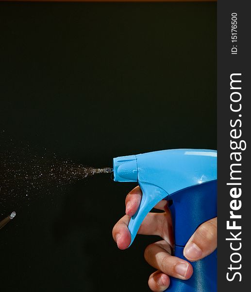 A bottle of disinfectant spraying isolated on black. A bottle of disinfectant spraying isolated on black