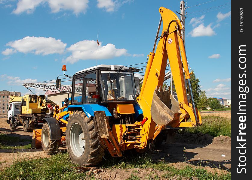 Excavator and crane on background of blue sky with clouds