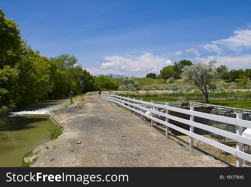 Urban scene of a country road along side a farm and flowing stream. Urban scene of a country road along side a farm and flowing stream
