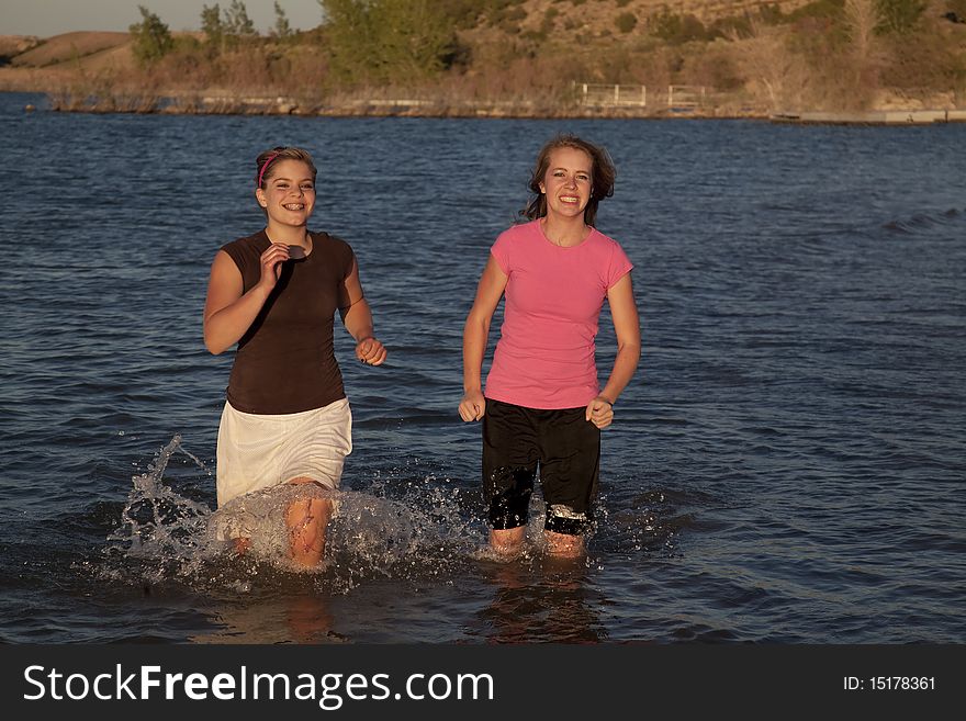 Two girls racing in the water and smiling. Two girls racing in the water and smiling.