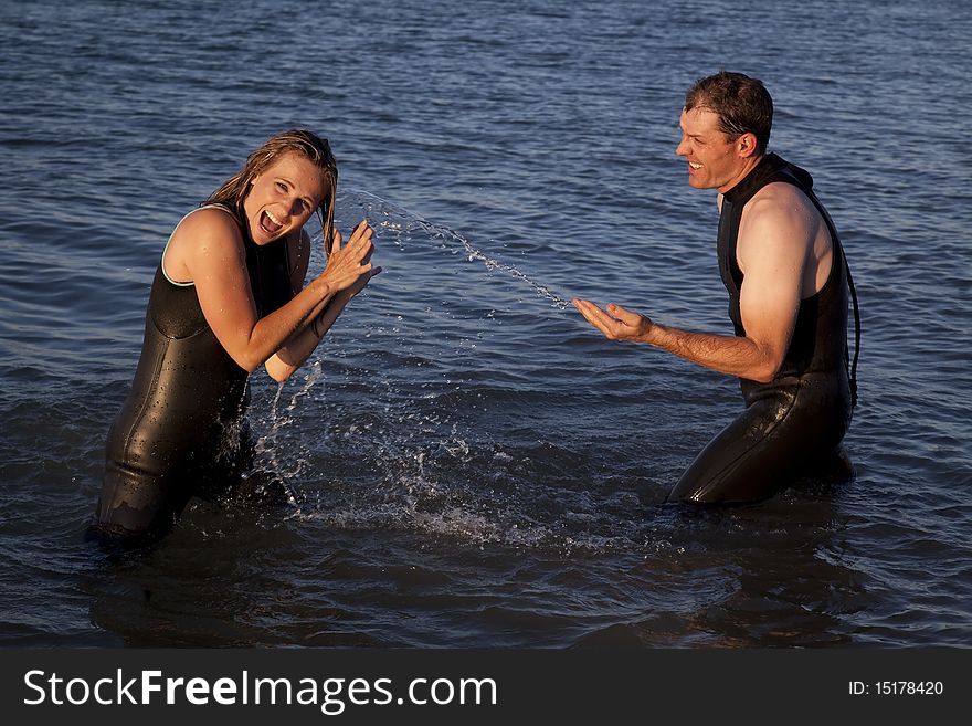 A woman with a surprised expression getting splashed by a man while they are in the water. A woman with a surprised expression getting splashed by a man while they are in the water.