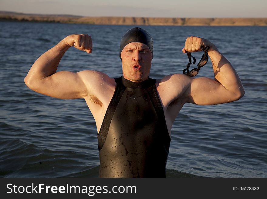 A man standing in the water showing off his muscles. A man standing in the water showing off his muscles.