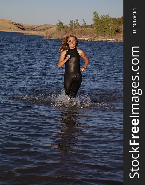 A woman in her wet suit running in the water getting ready to dive in. A woman in her wet suit running in the water getting ready to dive in.