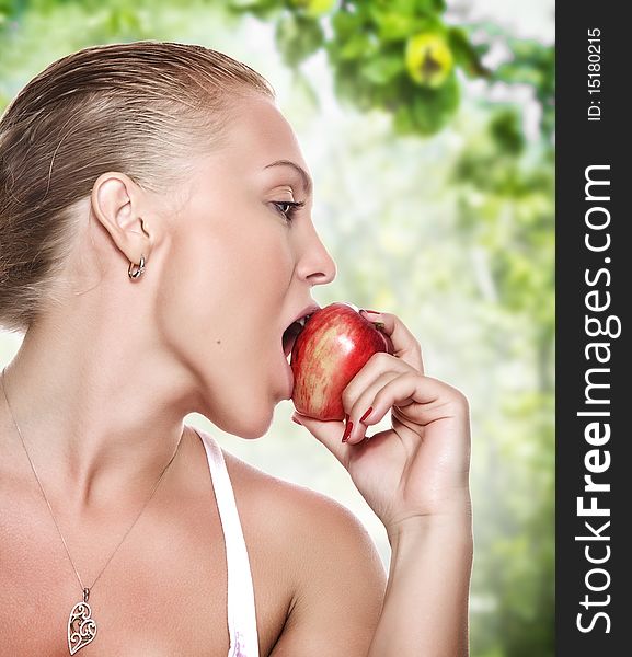 Portrait of young beautiful woman biting apple on blue back. Portrait of young beautiful woman biting apple on blue back