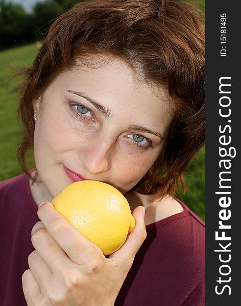 A beautiful girl is holding a lemon ,grass background