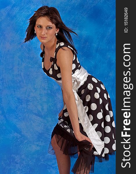 Beautiful girl on the blue mosaic background in a polka-dot dress. Beautiful girl on the blue mosaic background in a polka-dot dress