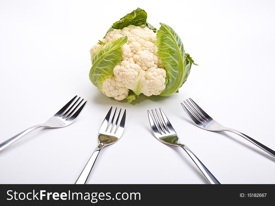 Cauliflower and four forks laying on a table. Cauliflower and four forks laying on a table