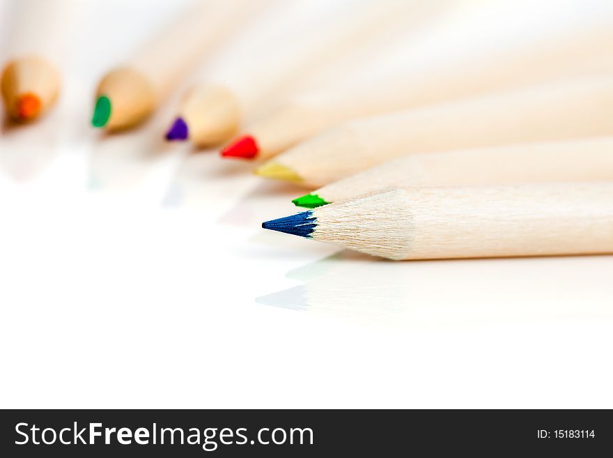 Many colored pencils in row over white background
