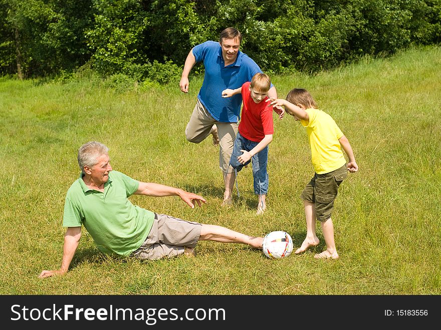 Happy family playing soccer on the grass