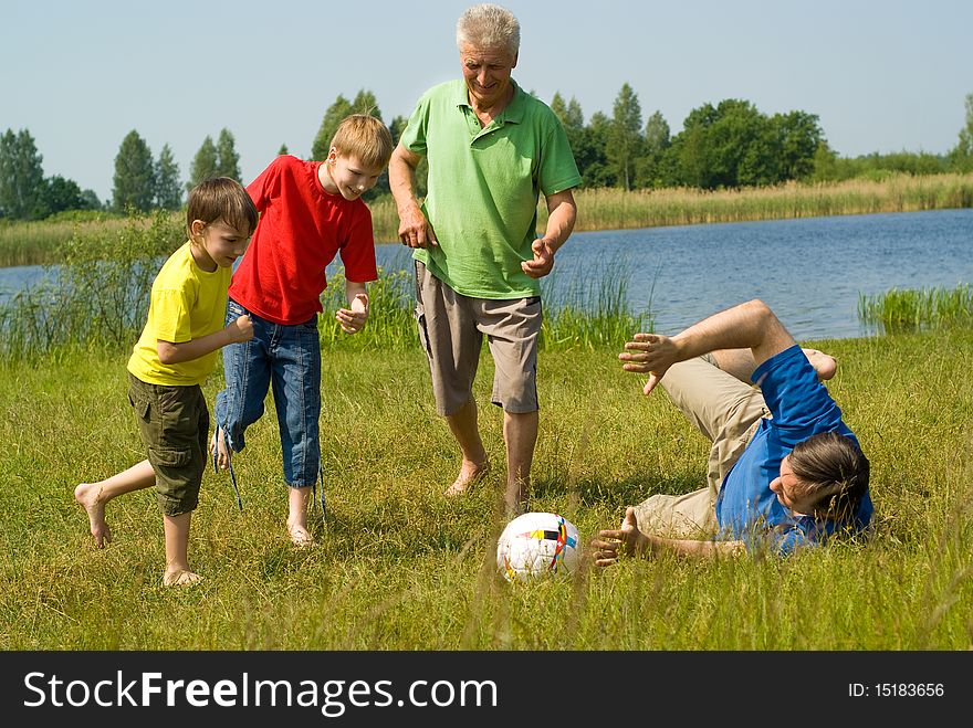 Family Playing Soccer On The Grass