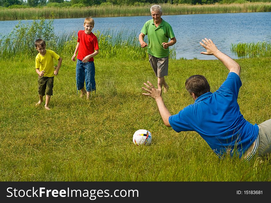 Happy family playing soccer on the grass