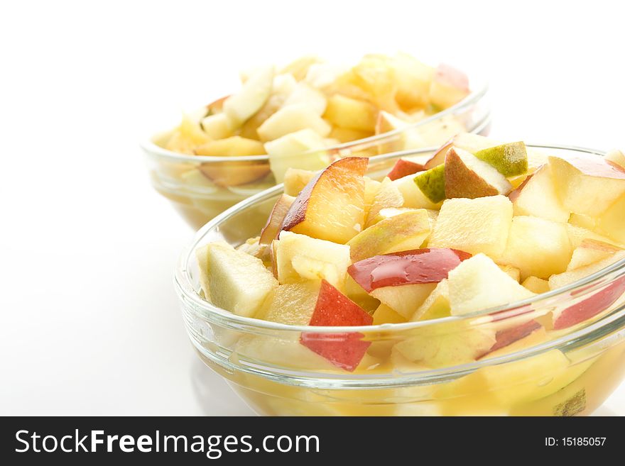 Fruit salad with apples, oranges, peaches, pears and orange juice. Decomposed in two glass plates. Isolated on white background