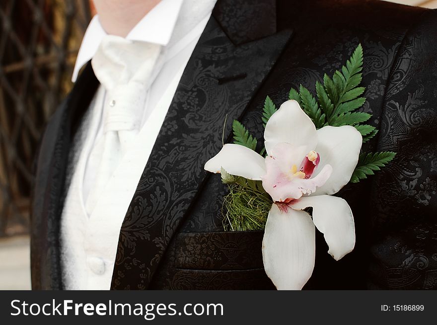 Detail of a groom's suit with a beautiful orchid flower