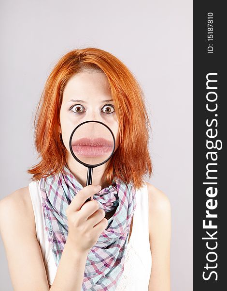 Beautiful red-haired girl with loupe zooming her mouth.