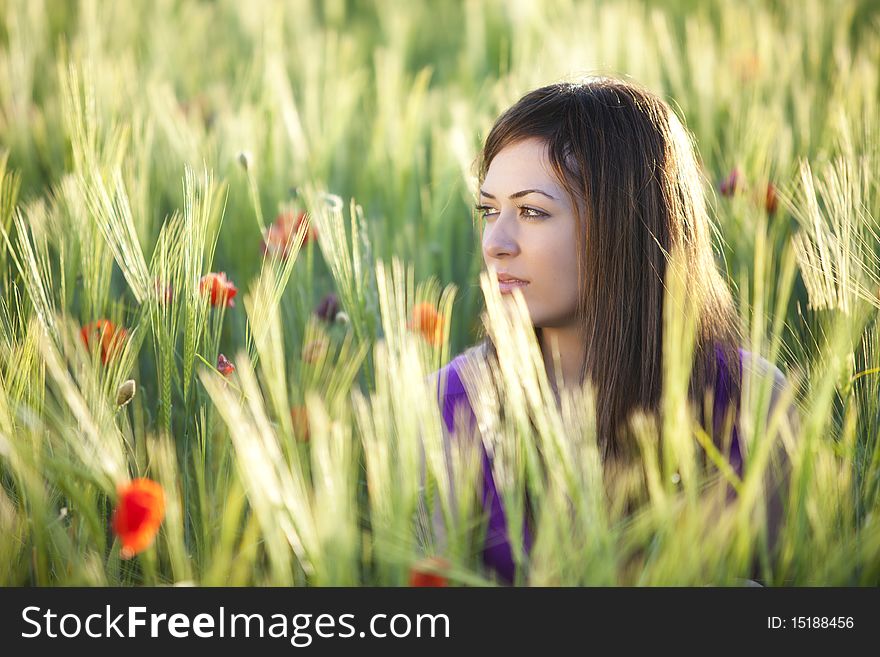 Young beautiful girl posing in a green field. Young beautiful girl posing in a green field.