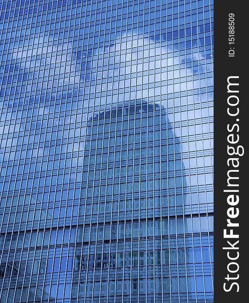 Cloud reflection in a skyscraper at Canary Wharf in London; contrast between architecture and weather