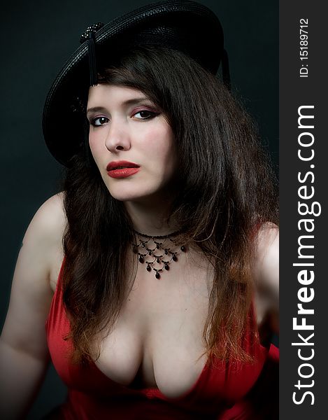 busty woman wearing vintage hat with tassles and low cut red dress. busty woman wearing vintage hat with tassles and low cut red dress