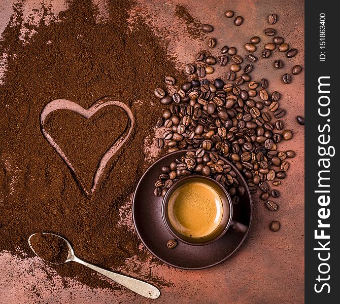 A cup of creamy espresso, a pile of ground coffee with a drawing of a heart. A cup of creamy espresso, a pile of ground coffee with a drawing of a heart