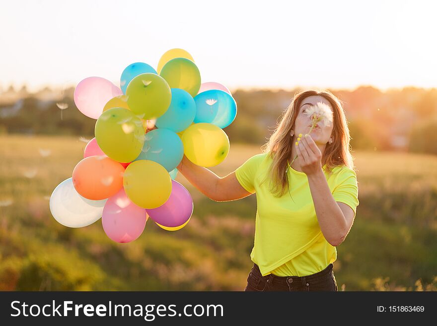 Happiness or dream concept, happy woman with multicolored balloons and dandelion at sunset. party, freedom, summertime. Happiness or dream concept, happy woman with multicolored balloons and dandelion at sunset. party, freedom, summertime