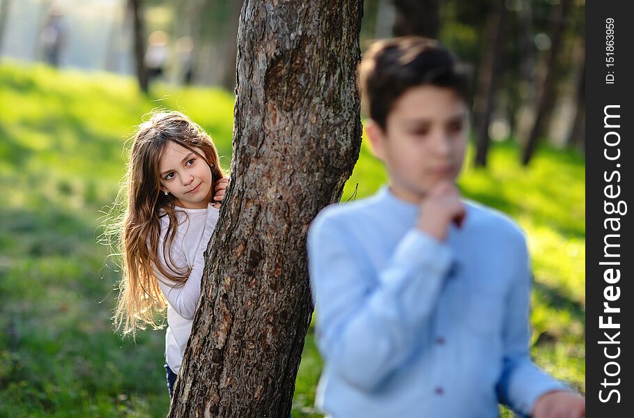 Girl hiding behind the tree and lurk on boy. Girl hiding behind the tree and lurk on boy.