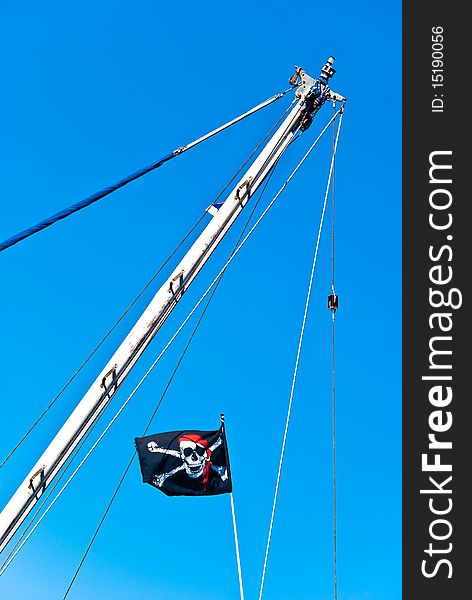 Pirate flag on the mast isolated on deep blue sky