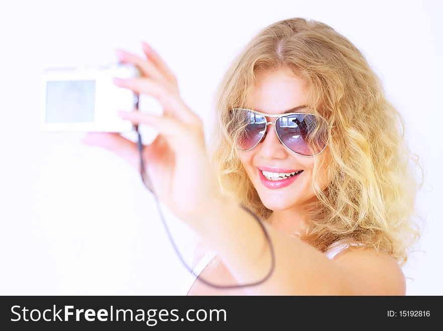 Stylish girl holding a camera on a light background