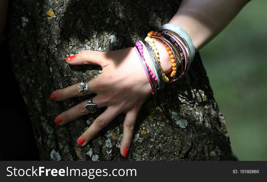 Woman hand with all kinds of adornment cling to the tree trunk