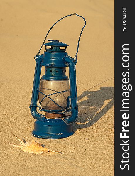 Vintage blue gasoline lantern and sea shell on the sand background. Vintage blue gasoline lantern and sea shell on the sand background
