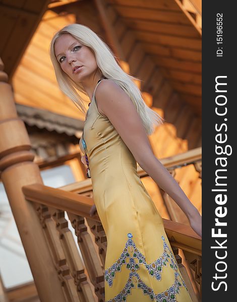 Glamour woman in evening dress, wooden house in background