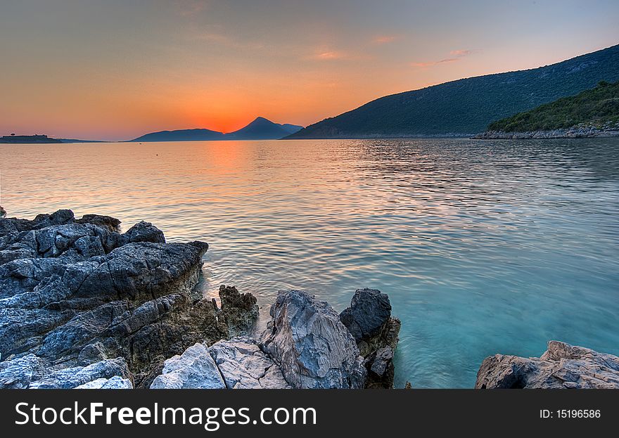 Beautiful summer sunset at the Adriatic see, Montenegro. Shot minutes after the sun set behind the distant mountain which is a border line between Montenegro and Croatia. Beautiful summer sunset at the Adriatic see, Montenegro. Shot minutes after the sun set behind the distant mountain which is a border line between Montenegro and Croatia