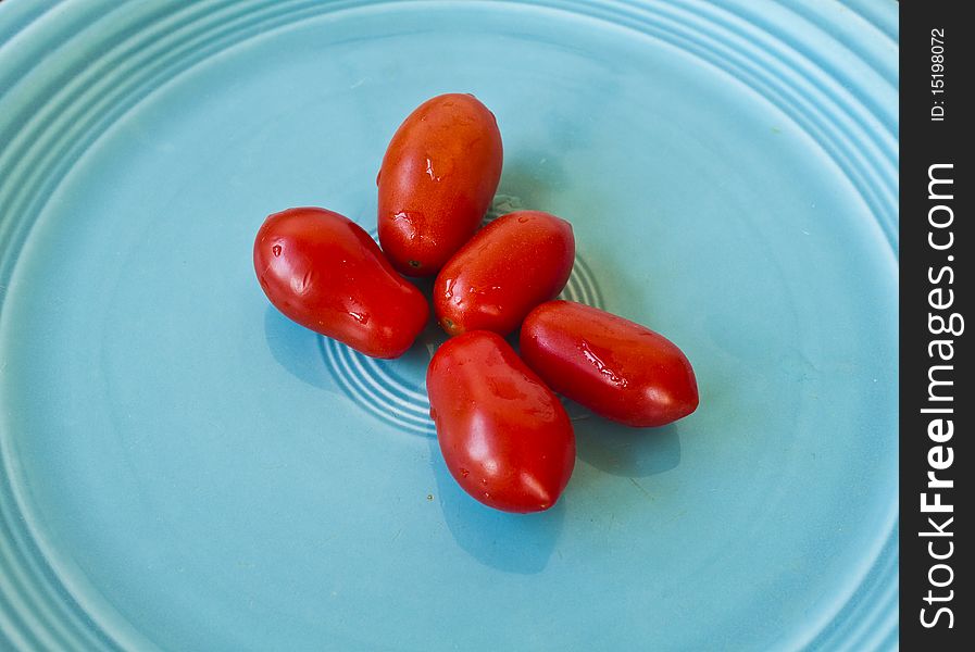 Pear shaped tomatos on a turquoise plate.