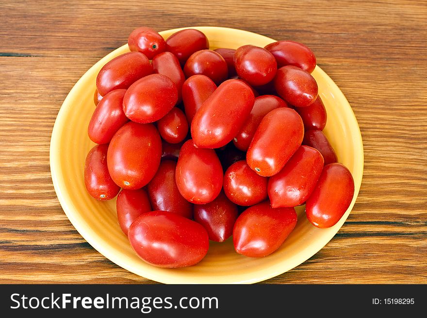 Plate full of tomatos in a yellow plate on a table