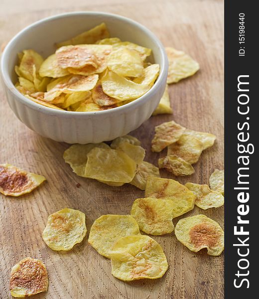 Potato chips in a bowl and scattered on a table