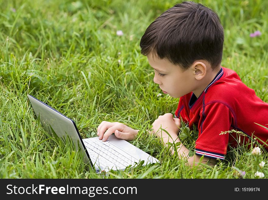 Small boy using notebook outdoor on grass