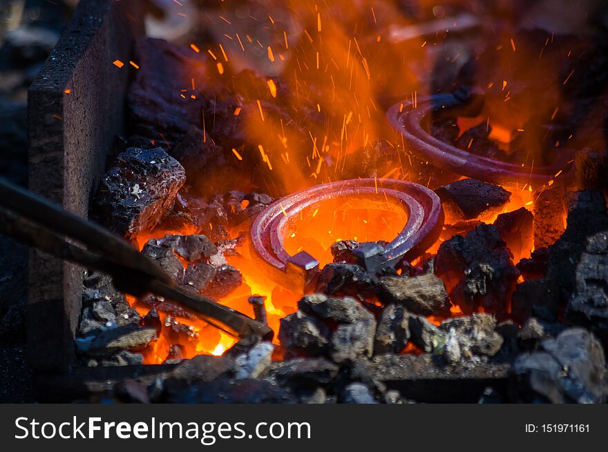 blacksmith furnace with burning coals, tools, and glowing hot horseshoe, close-up