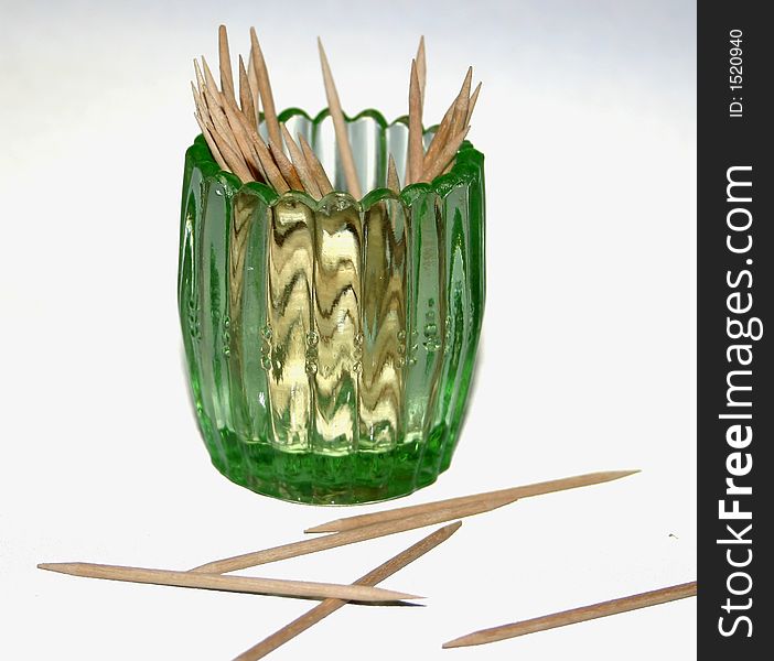 A green depression era glass toothpick holder with toothpicks.