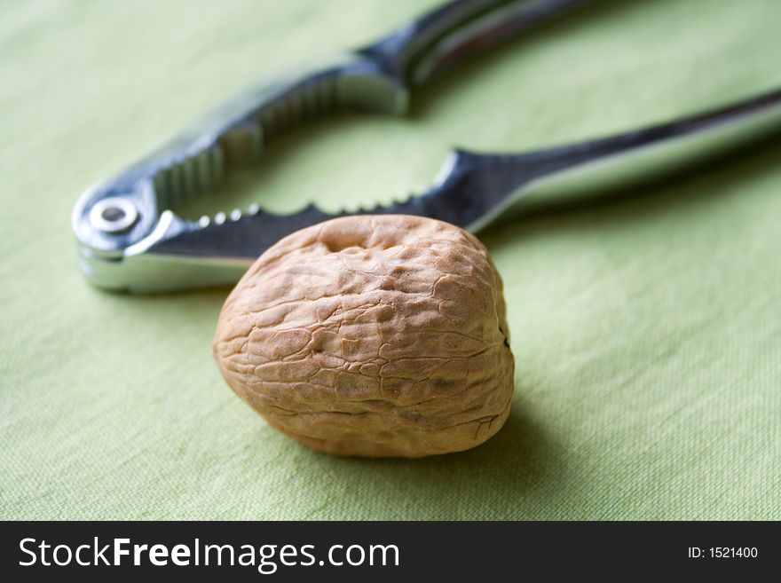 Lonely walnut and nutcracker on green tablecloth